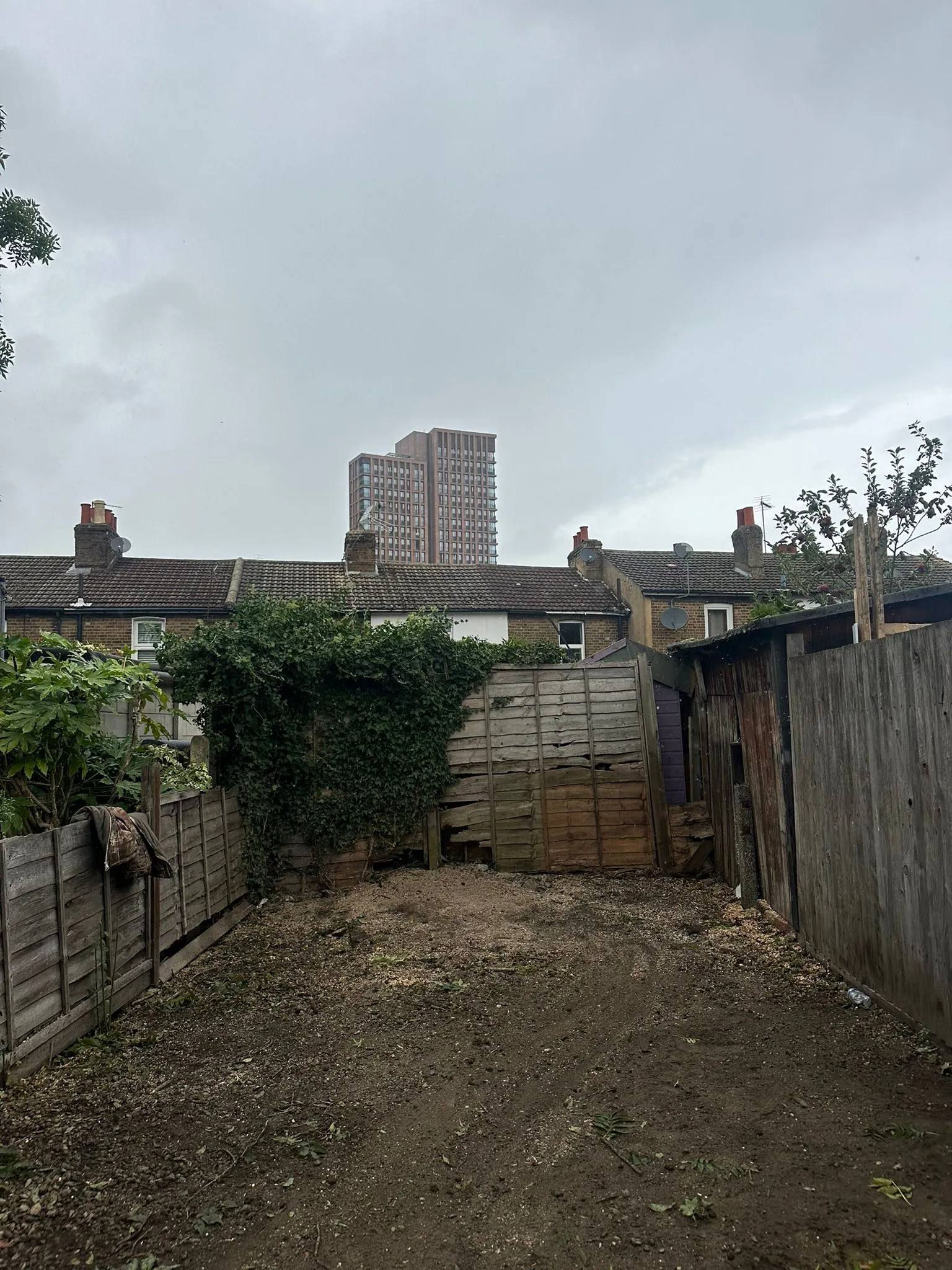 A dirt yard with a fence and buildings in the background.